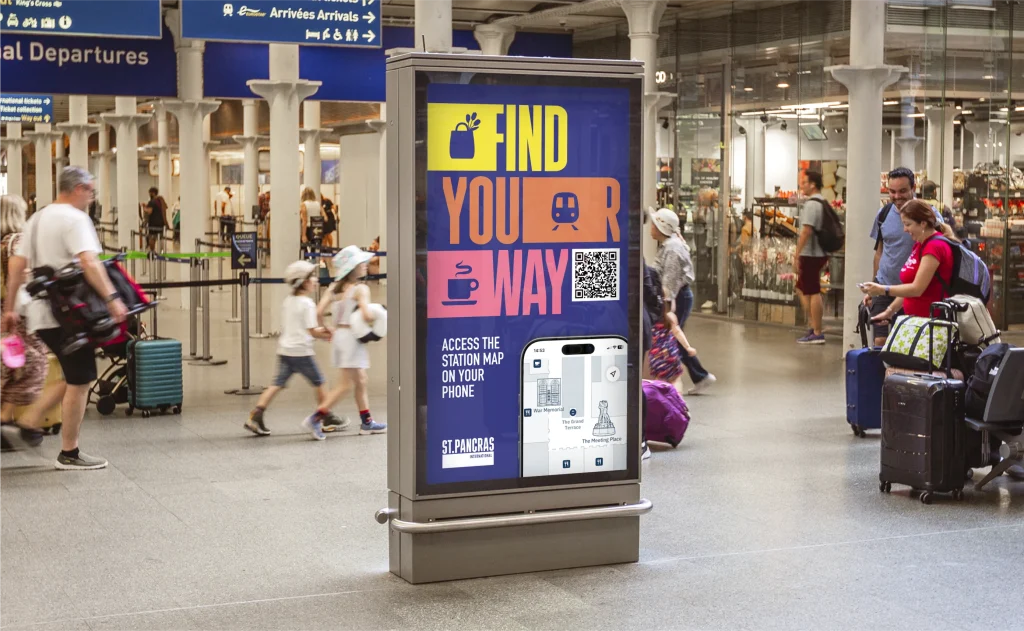 "Find your Way" Static poster for St Pancras station, advertising the St Pancras Station Map for mobile. The F, R, and W are elongated horizontally to show a flower bag, train and coffee icon. Photographed in St Pancras Station on a digital interactive screen.