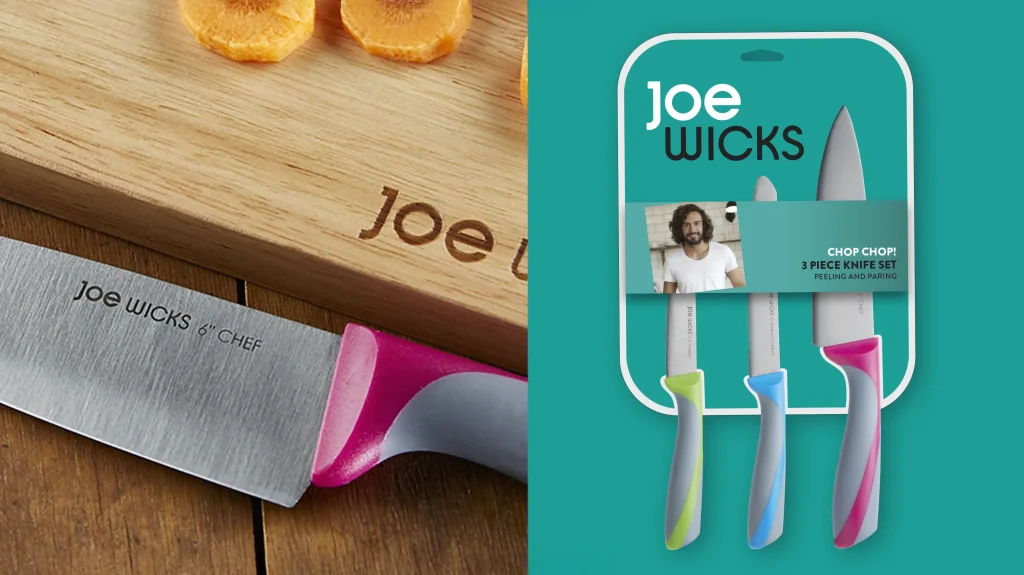 Close up photography of a Joe Wicks branded knife and a Joe Wicks branded wooden chopping board, next to Joe Wicks "Chop Chop, 3 piece knife set" packaging.