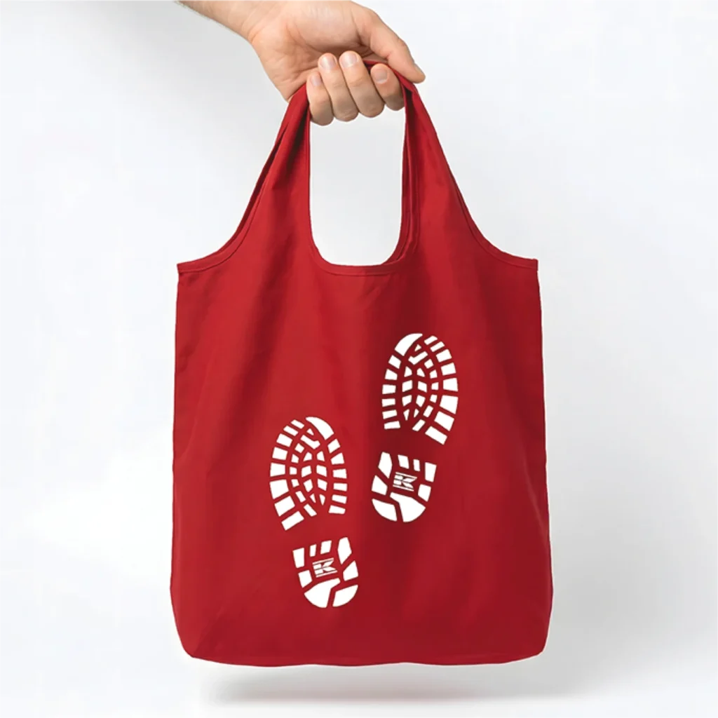 Red tote bag with two white Bootprints, with the Kramp logo on the sole, on the front