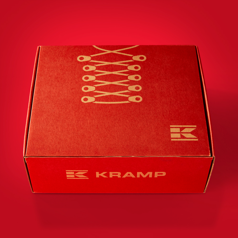 Red Kramp shoe box, shot at a 3/4 angle, against a red background.