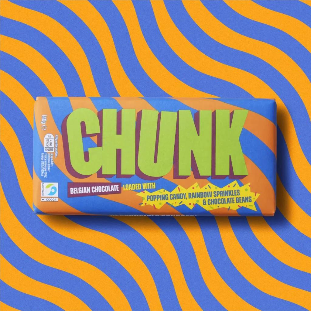 Popping Candy, Rainbow Sprinkles & Sea Salt Chunk chocolate bar photographed on top of a wavy orange and blue background.