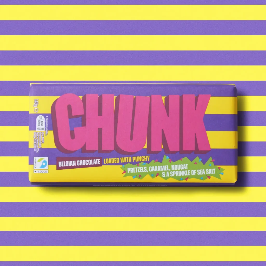 Pretzels, Caramel, Nougat & Sea Salt Chunk chocolate bar photographed on top of a horizontally striped purple and yellow background.