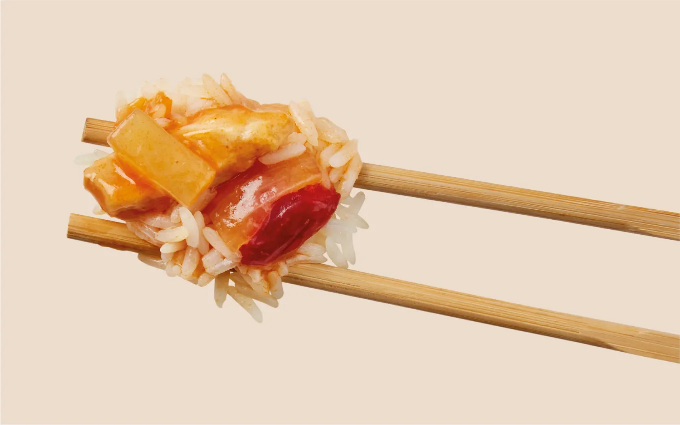 Photography of sweet and sour chicken with rice between two chopsticks.